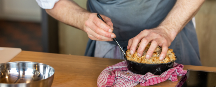 A chef using a knife to take a cake out of a tin