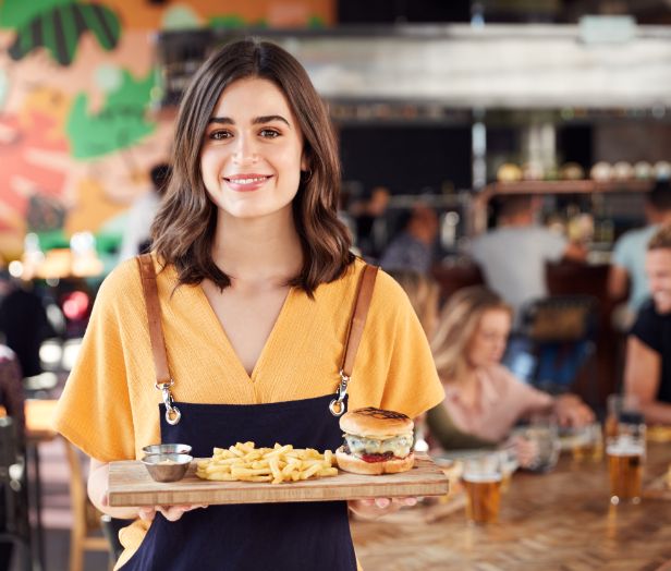 A waitress in a bar with burgers and chips