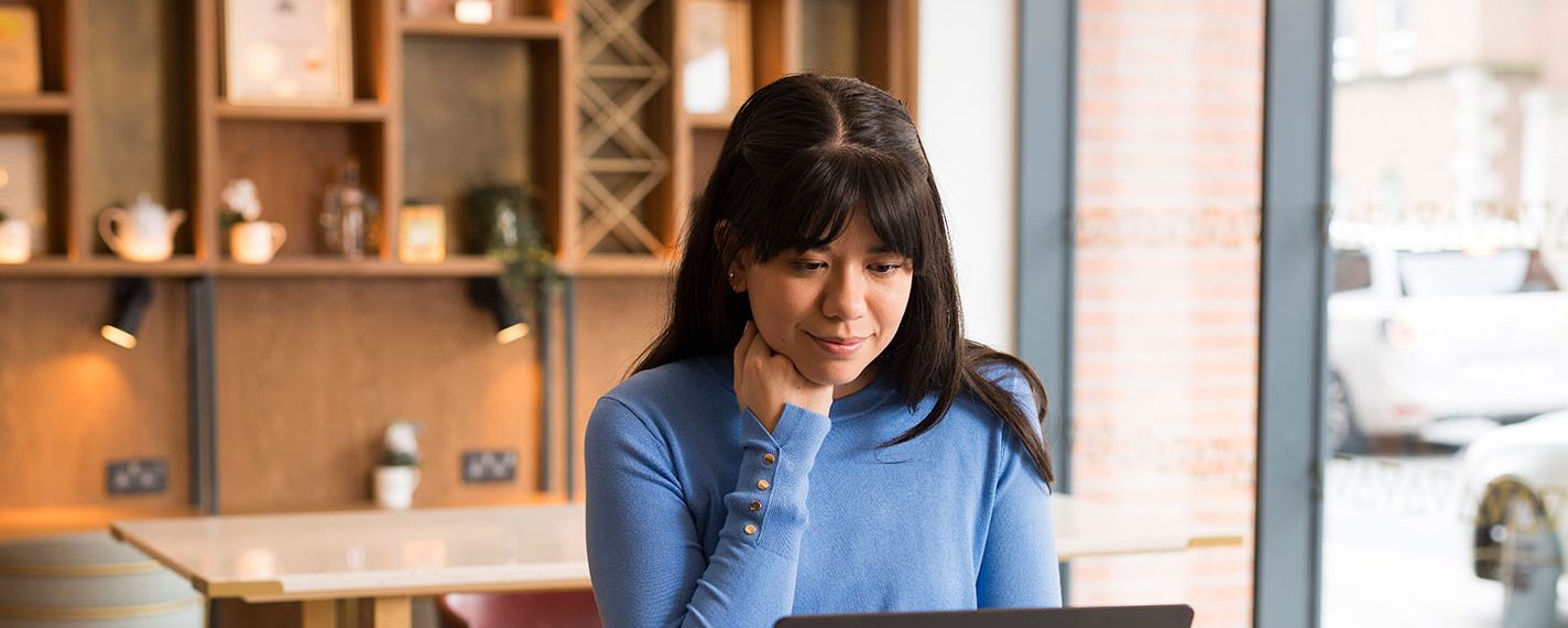 Woman smiles at laptop in cafe
