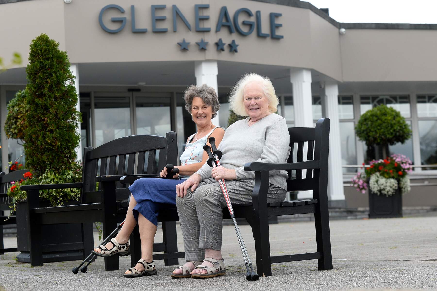 two women sitting on a bench outside a hotel