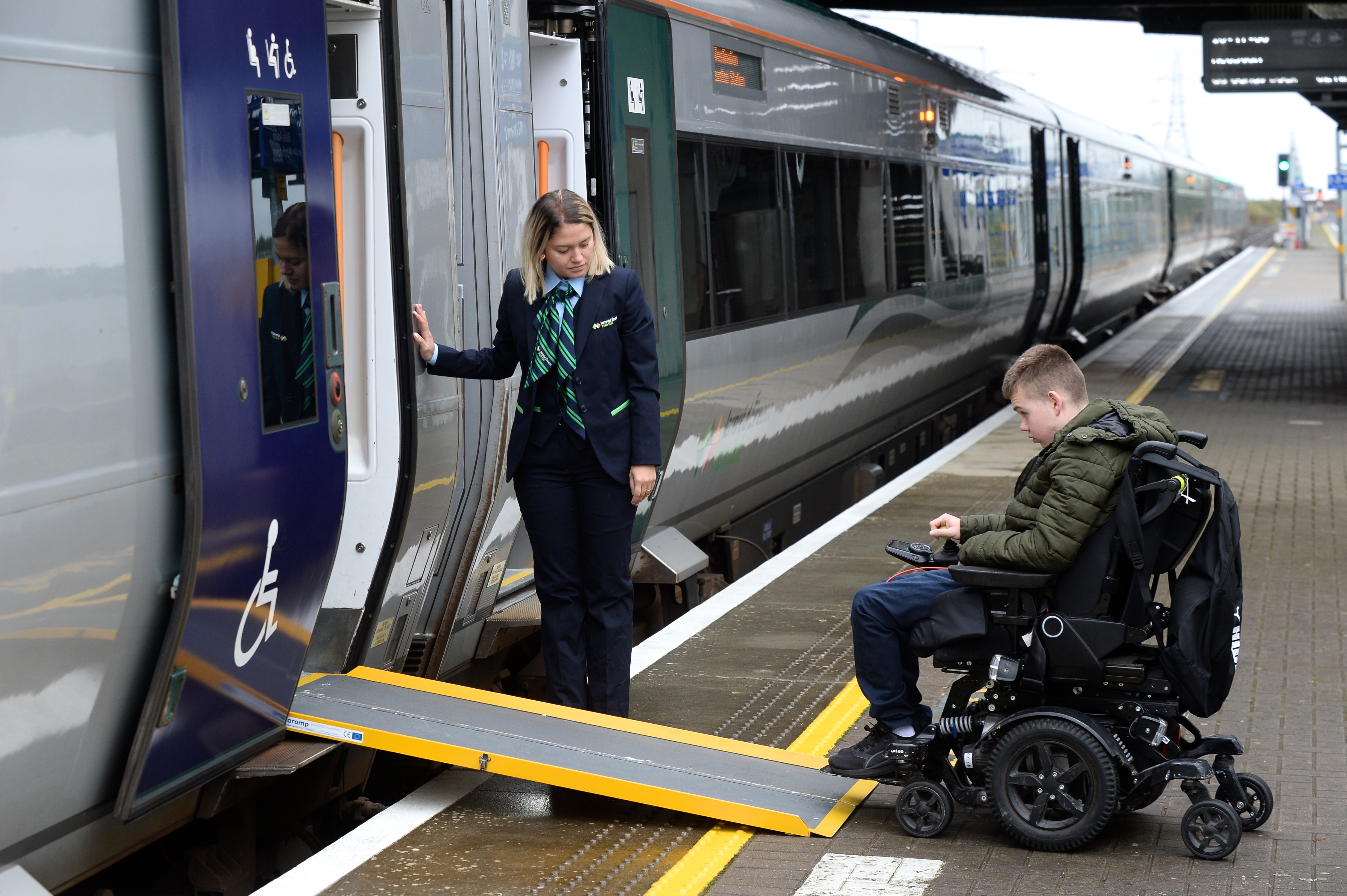 Man in wheelchair using ramp to board a train