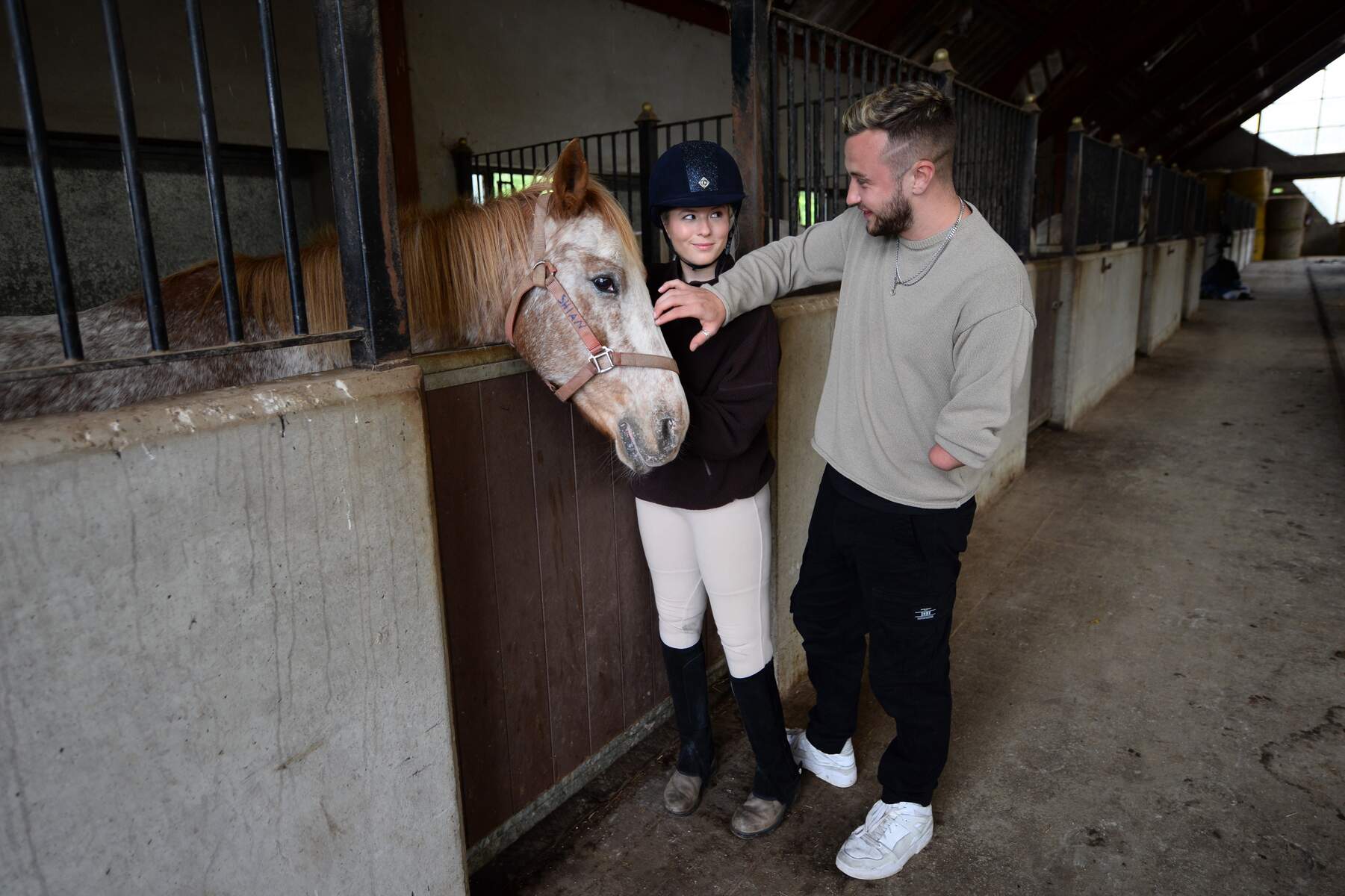 Man and woman petting horse in a stable