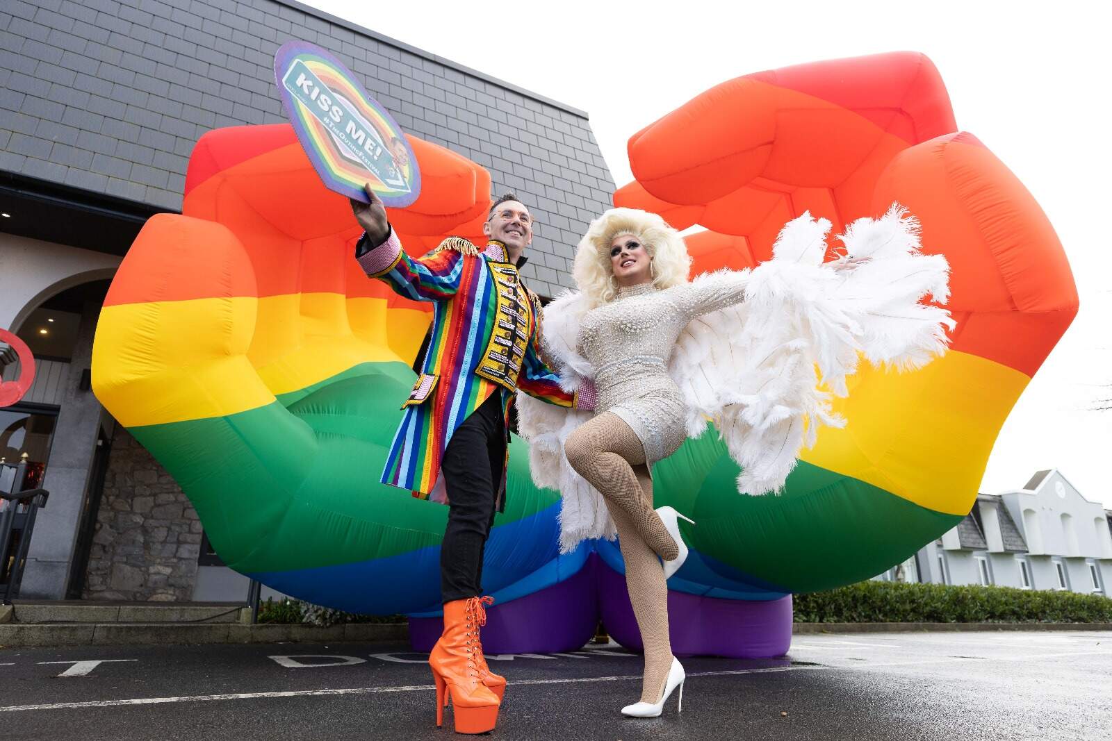 Man and woman dressed up with rainbow flag behind them