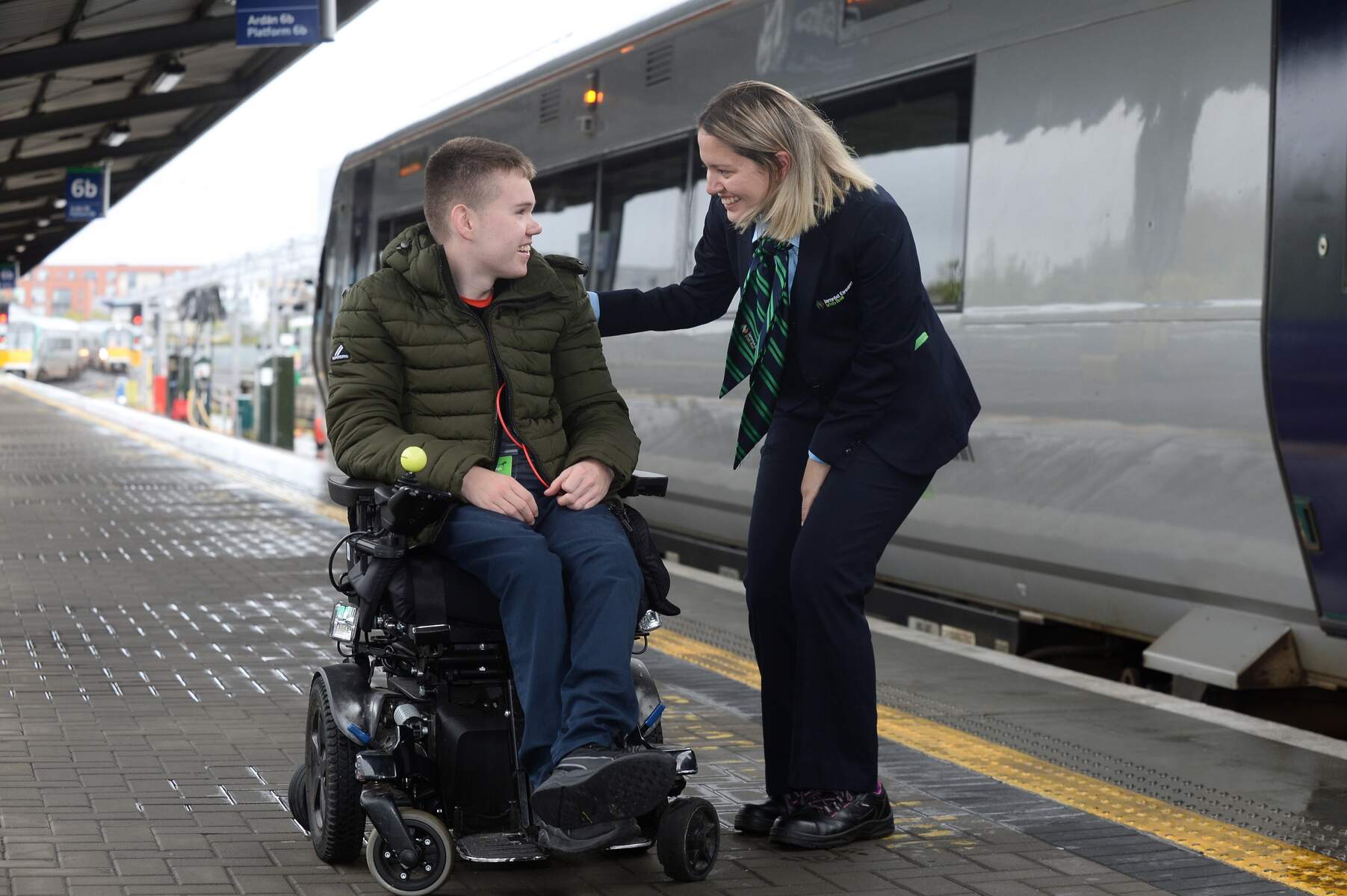 Man in wheelchair talking with woman at a train station