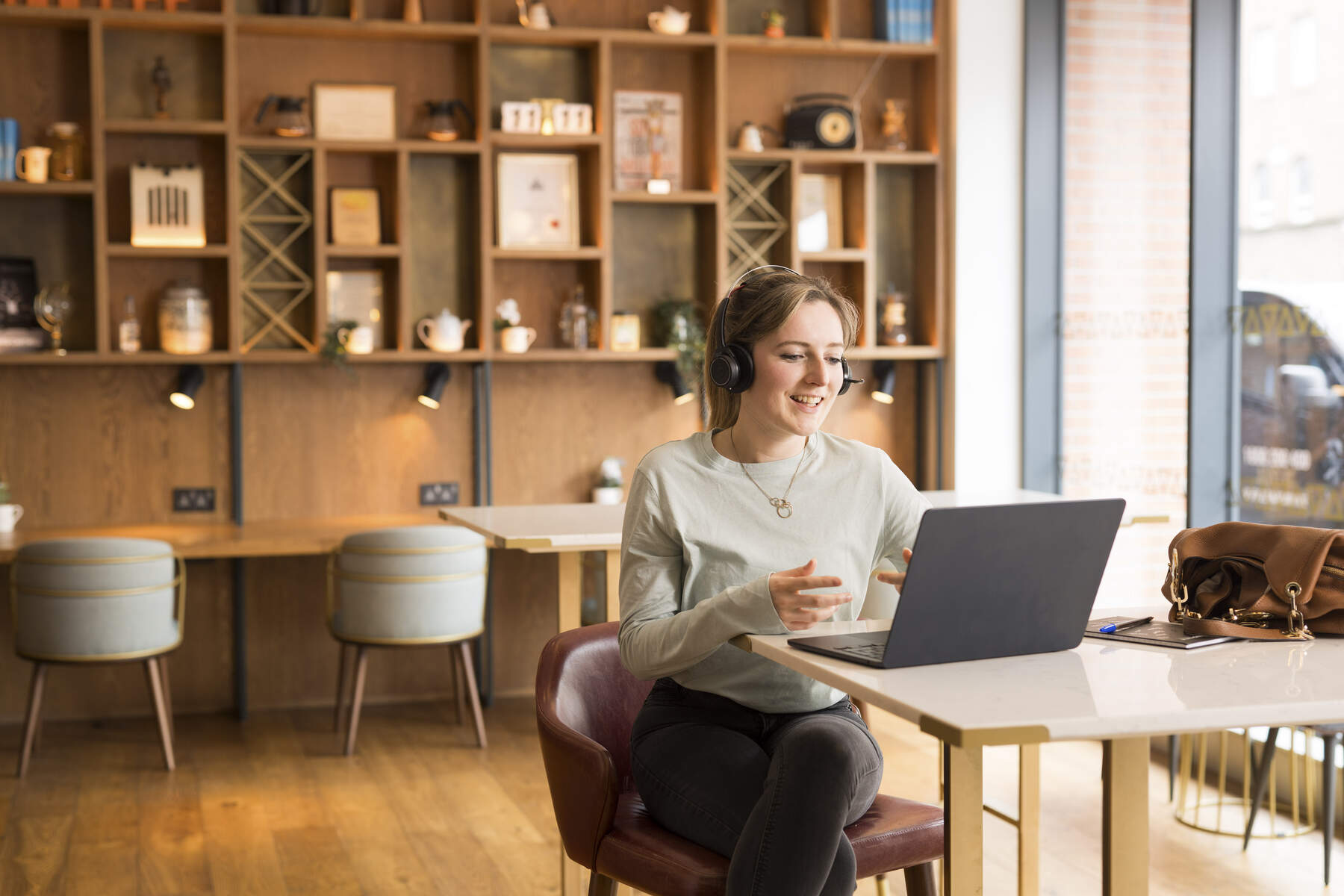 Woman with head phones sitting at a desk talking to a laptop