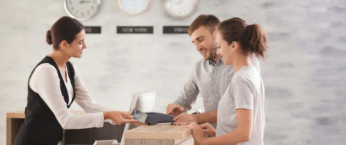 Female receptionist helps man and woman check into a hotel