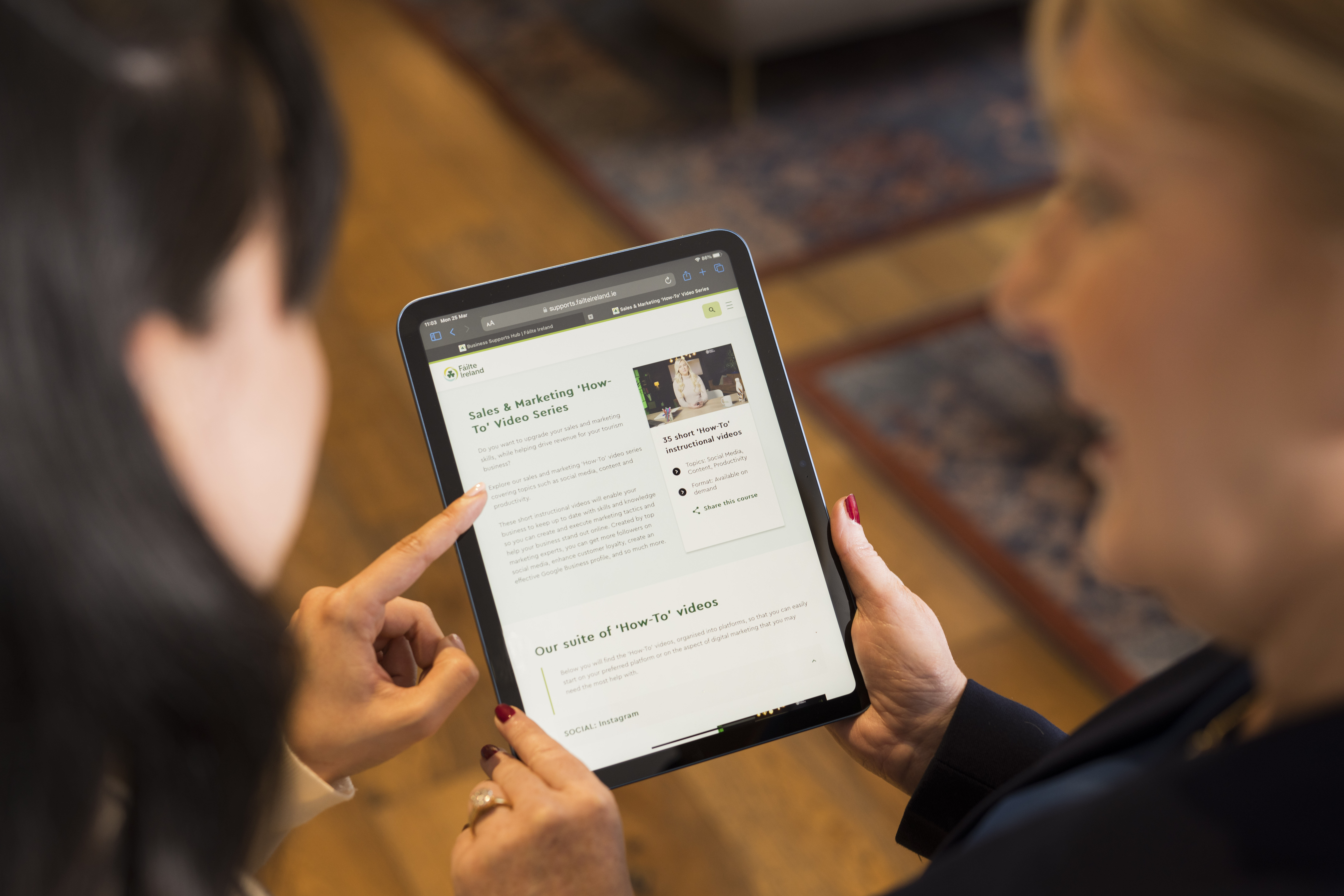 Two women looking at a tablet that has the Fáilte Ireland sales course page open