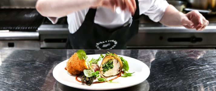 Chef sprinkling salt over a plate of food