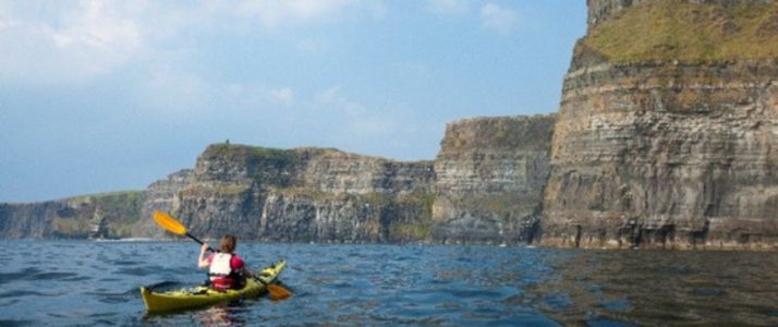 Person kayaking near cliffs on a sunny day