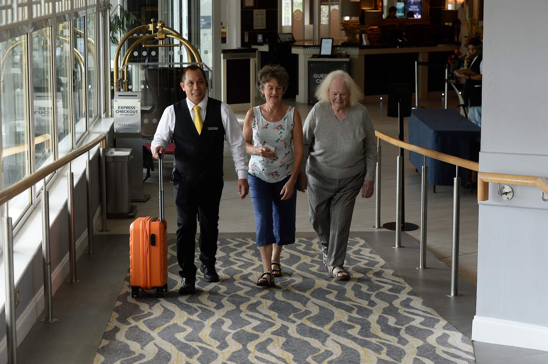 Two ladies and a man walking into a hotel lobby